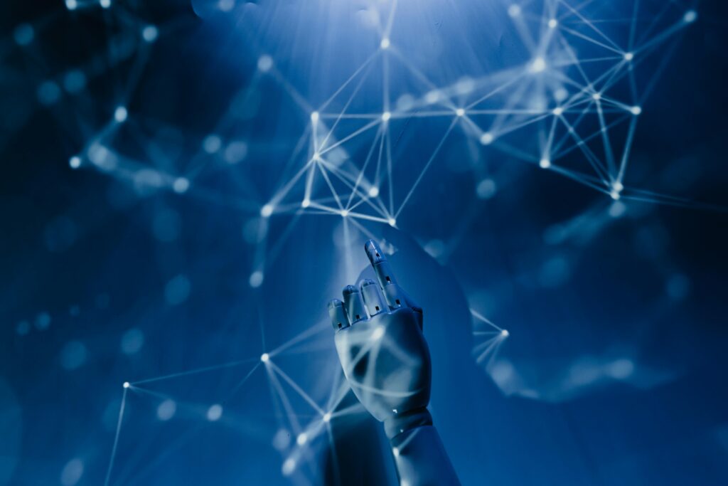 pexels-photo-8386440-8386440-1 A robotic hand reaching into a digital network on a blue background, symbolizing AI technology.